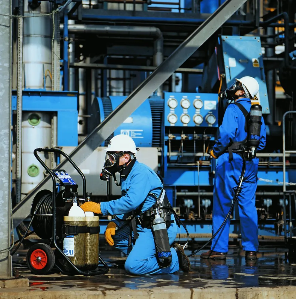 Equipe usando linha de ar mandado durante trabalho em área industrial