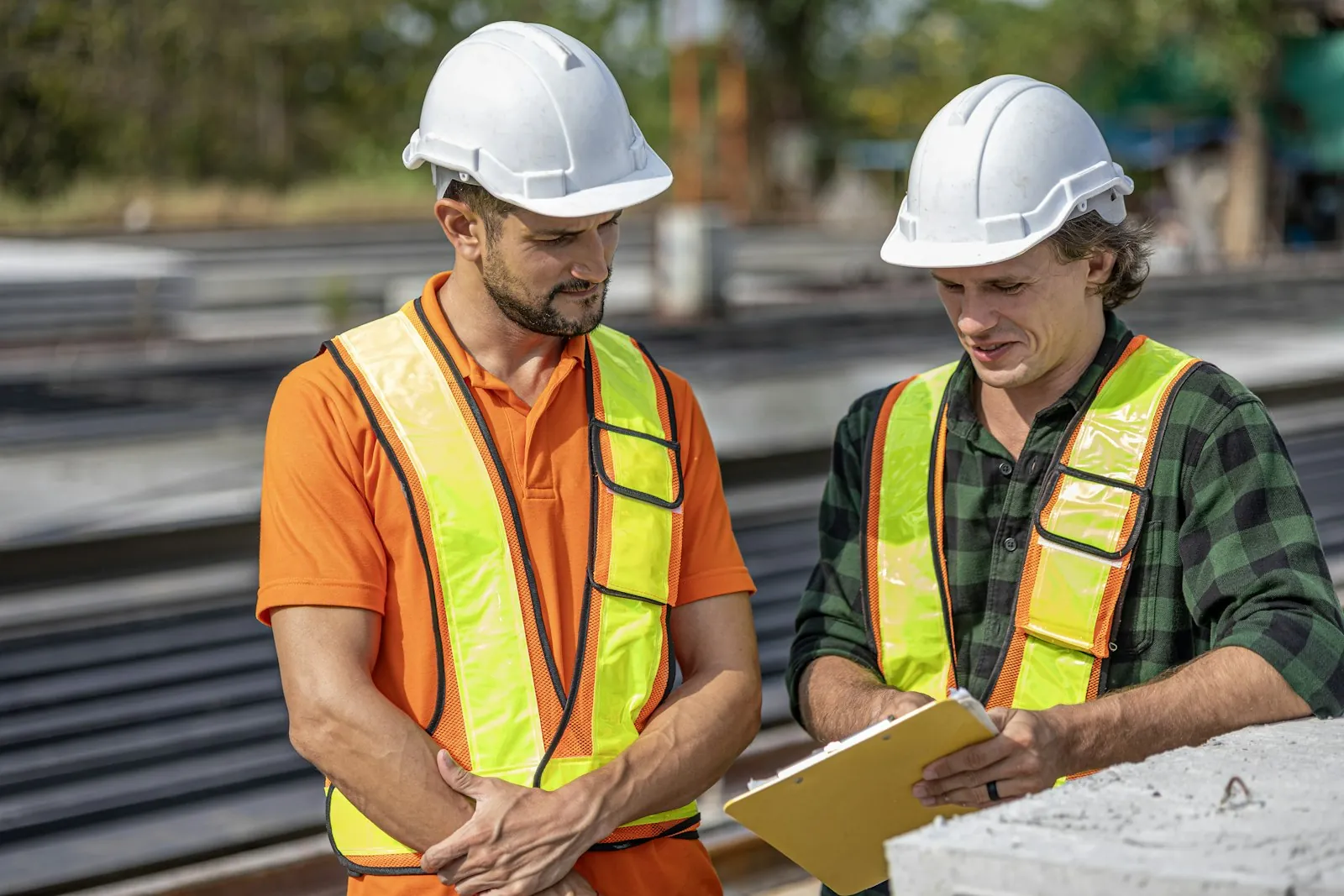 Técnicos de segurança com capacete e colete revisando uma inspeção em prancheta