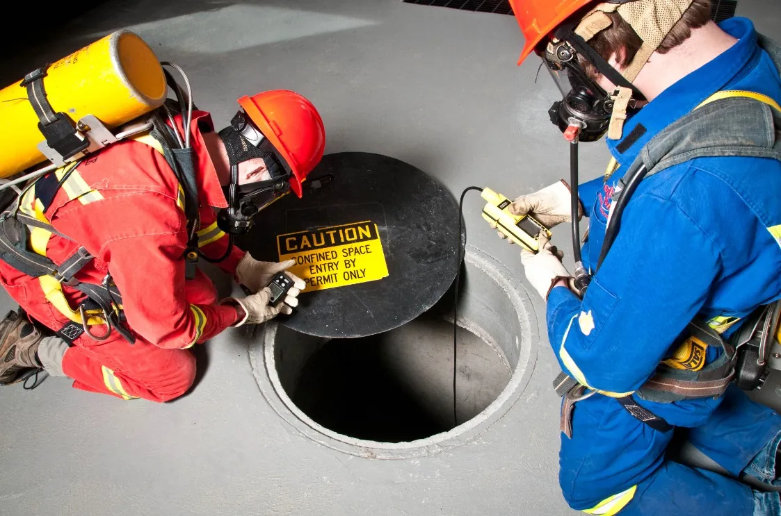 Equipe preparando a entrada em espaço confinado pela boca de visita com detector de gás